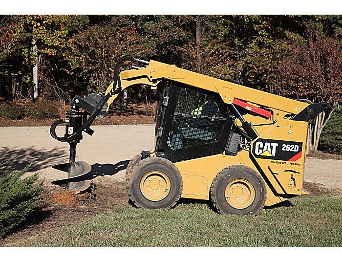 Skid steer loader CAT 262D drilling hole into the ground